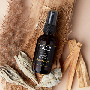 Doji natural deodorant, desert sage scent, overhead shot with sage smudge, palo santo wood pieces, and vetiver.