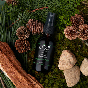 Doji natural deodorant, mountain pine scent, overhead shot on pine needles, pine cones, fir pine, cedar wood, and pebbles